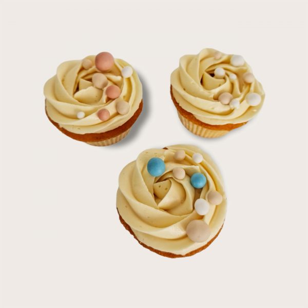 Trois cupcakes vanille avec une décoration multicolore et pochage de rose