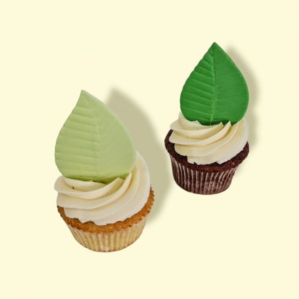 Deux cupcakes avec crème vanille et feuilles tropicales vert pâle et vert vif